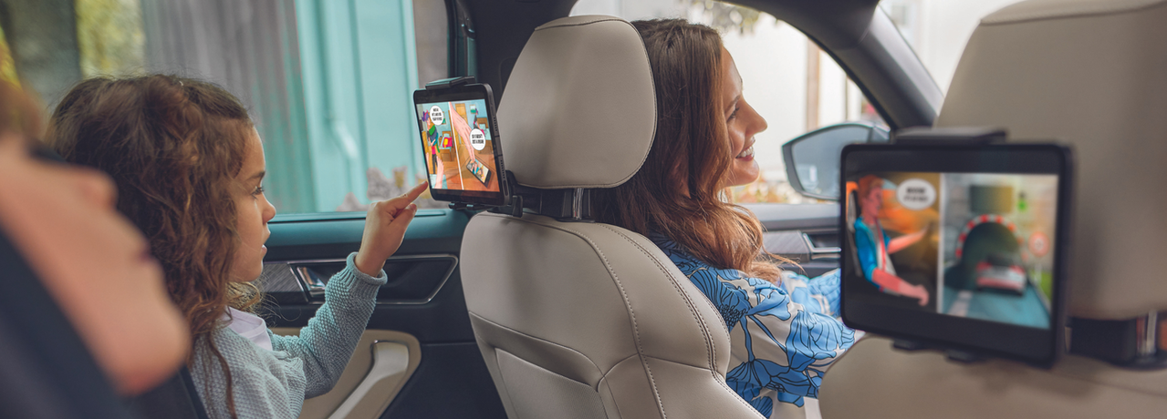 Familie sitzt im Auto und Kinder schauen auf Tablets