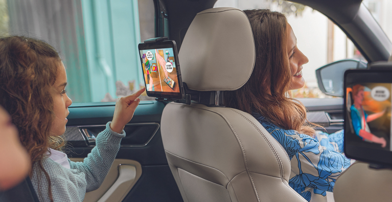 Familie sitzt im Auto und Kinder schauen auf Tablets