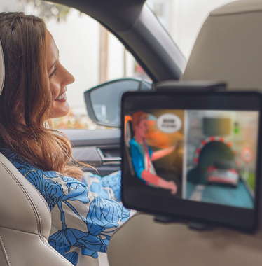 Familie sitzt im Auto und Kinder schauen auf Tablets